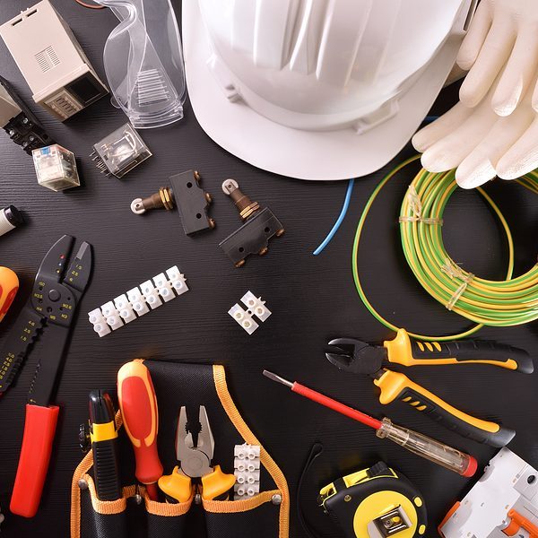 Black table with view from above looking at electrical tools, wires, screwdrivers, safety equipment and other equipment for electrical work